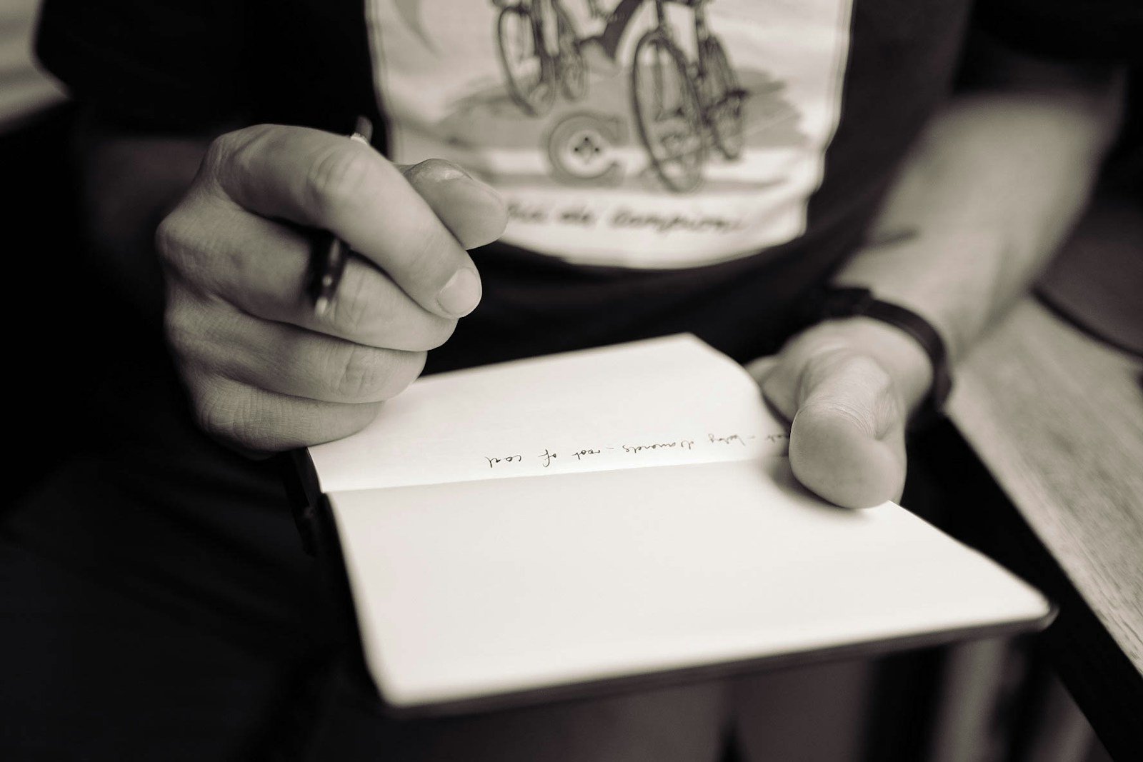 Fotografia ilustrativa em preto e branco de uma pessoa escrevendo em um caderno.